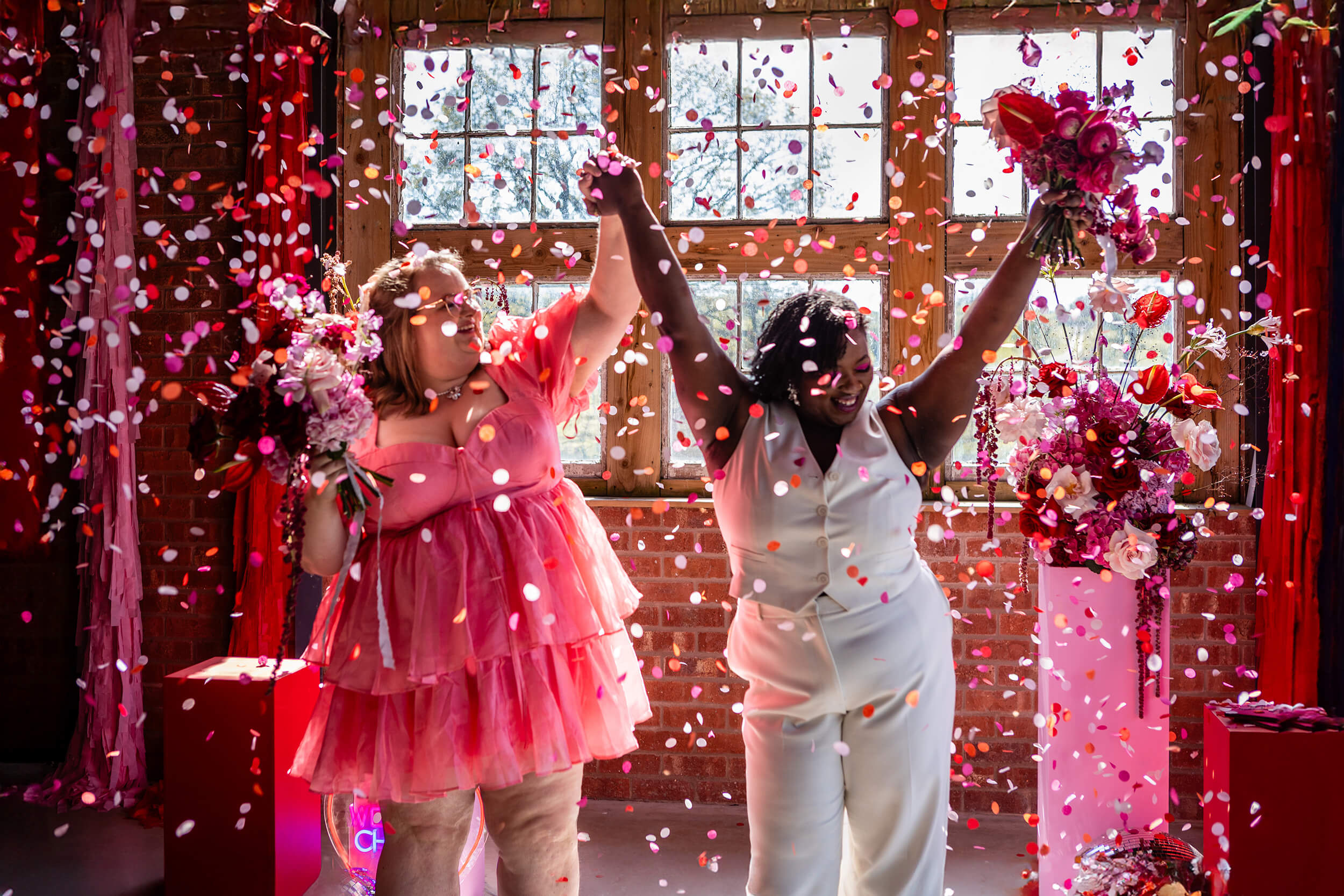 Two women celebrating with flowers and confetti | Pennard House wedding photographer 