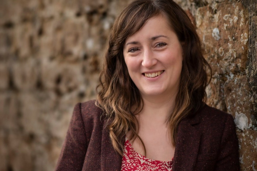 Smiling woman against textured stone wall.