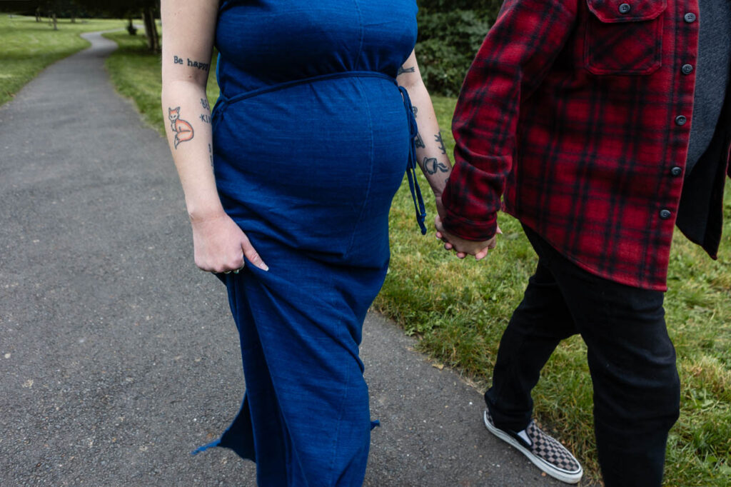 Pregnant woman holding hands with partner outdoors. Maternity Photography Bath Bristol Rose Dedman