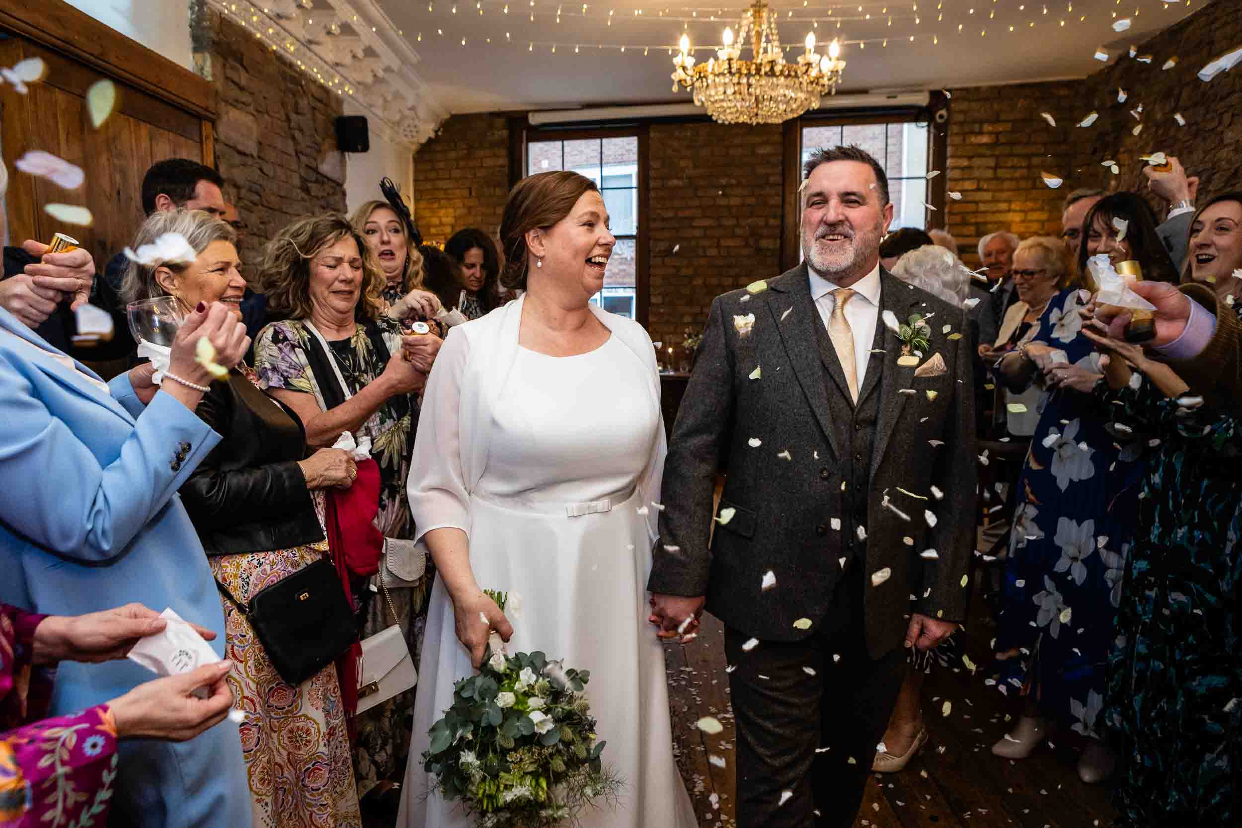 Bride and groom walk through confetti at The Radnor Rooms wedding venue, Bristol.