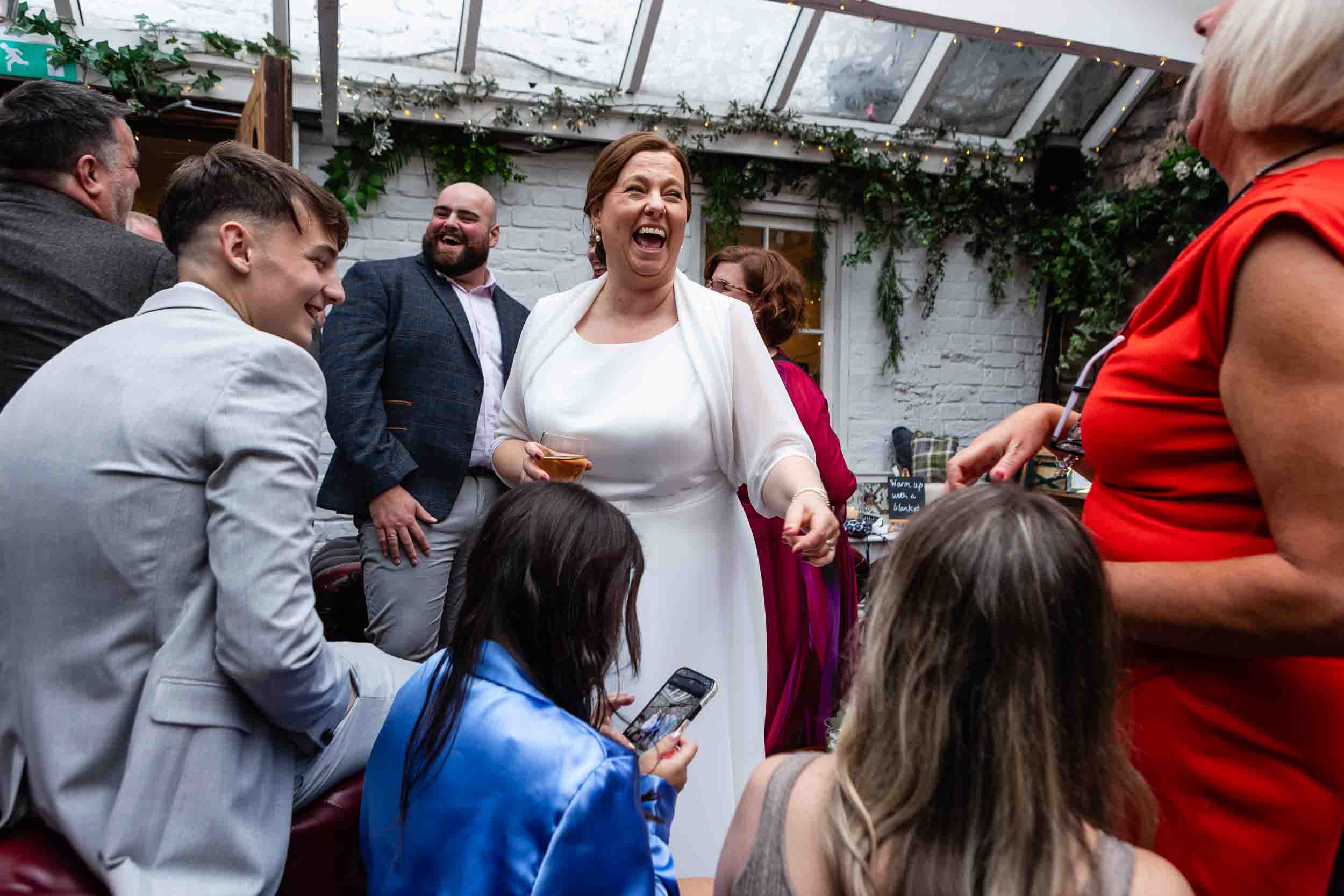 A bride laughs with guests during a wedding at The Radnor Rooms, Bristol.