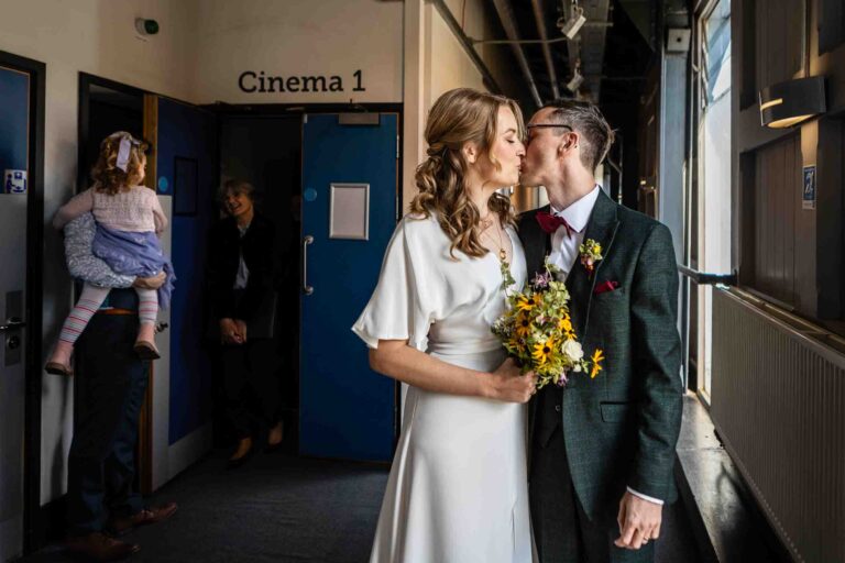 Bride and Groom kiss after exiting quirky cinema wedding ceremony at The Watershed | Bristol Wedding Photographer
