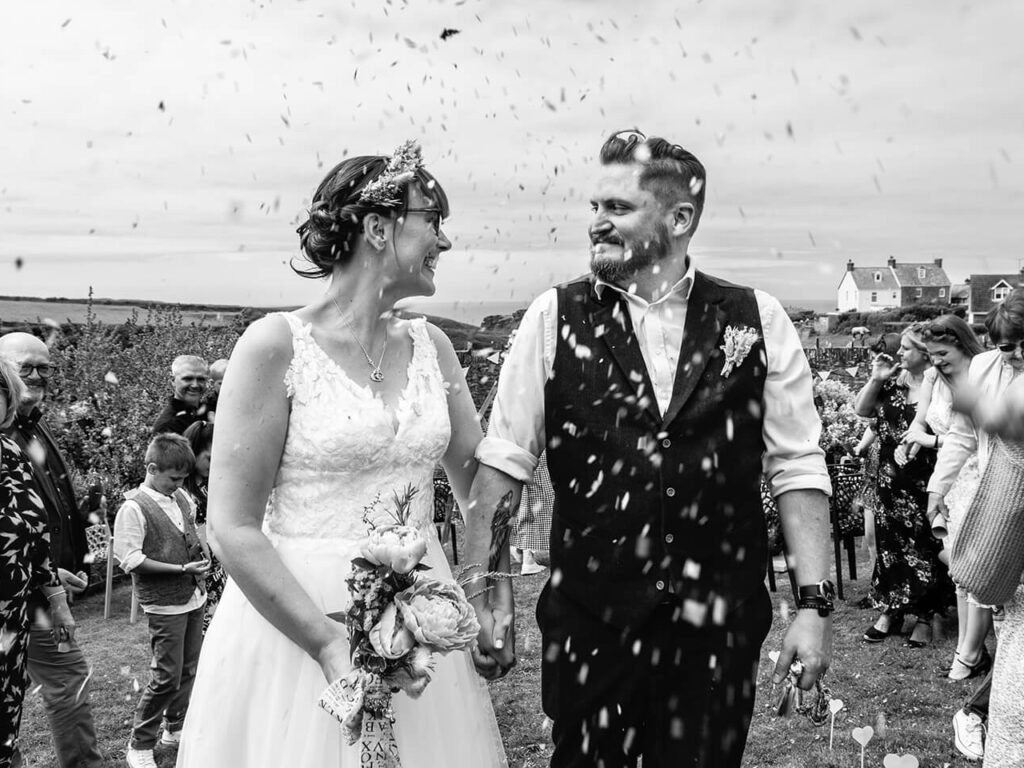 Bride and groom walking through confetti shower
