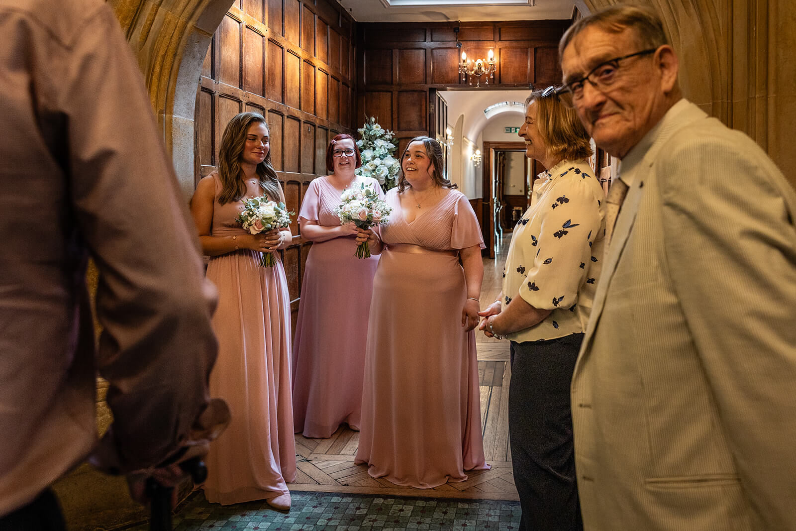 Bridesmaids in pink dresses holding flowers at Holmewood Hall. Somerset wedding photographer.