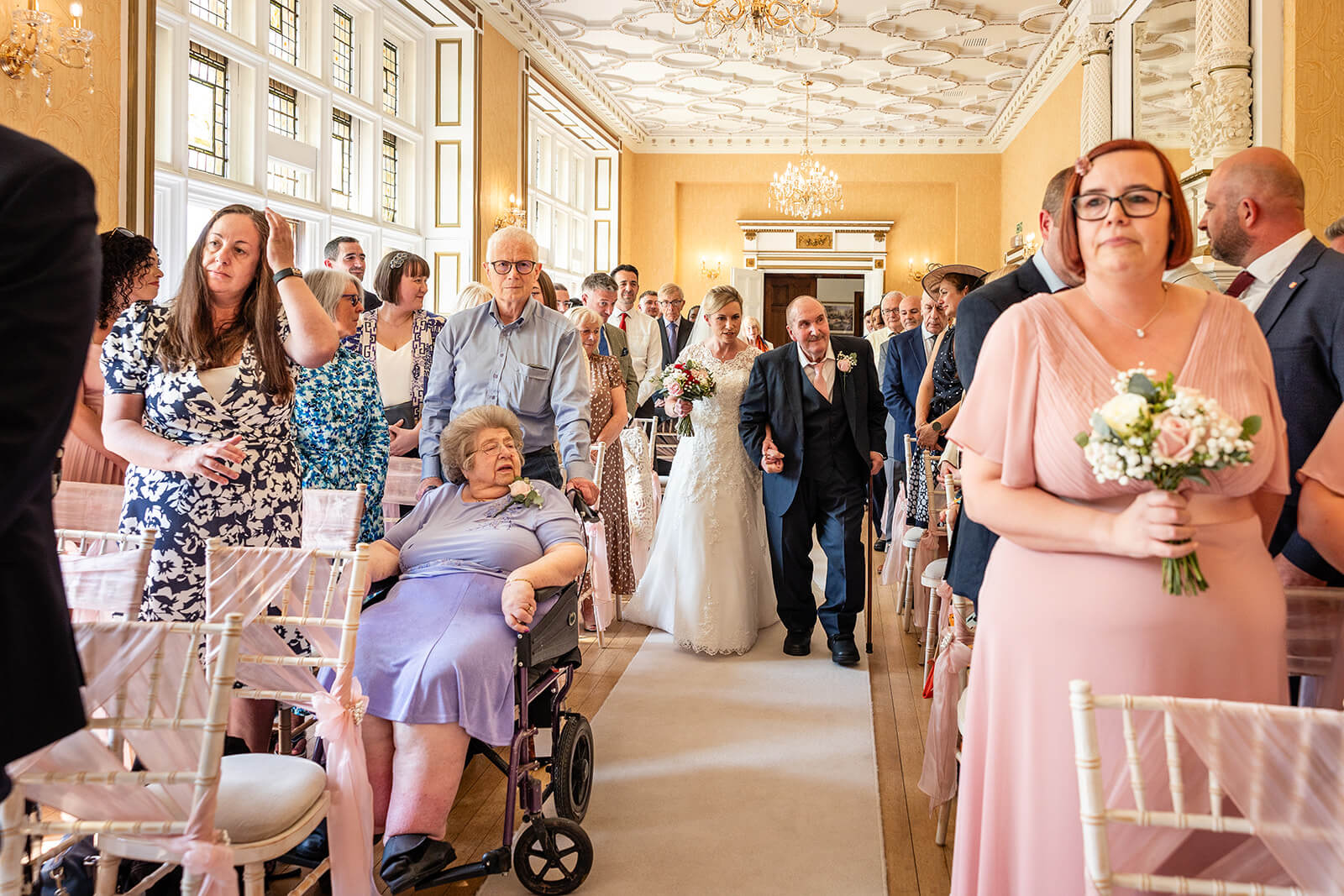 Bride walking down aisle with elderly man.