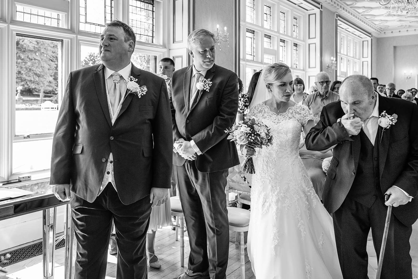 Bride walking down the aisle with family members.