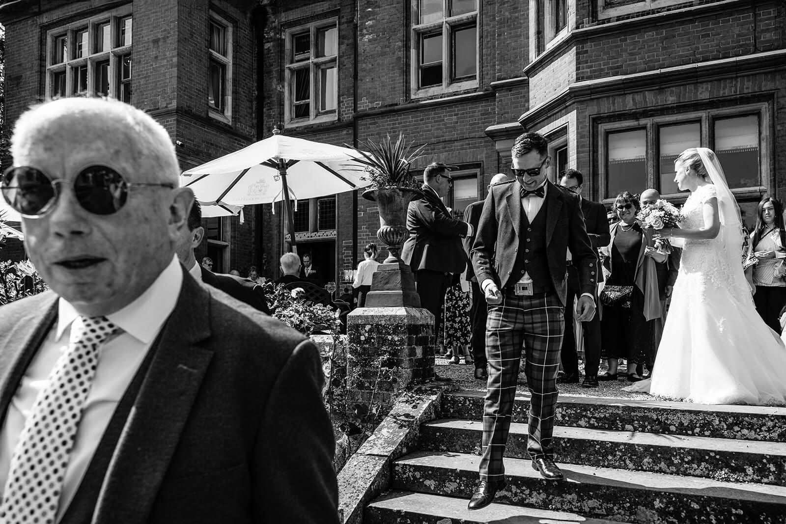 Wedding guests outside historic building, black and white photo.