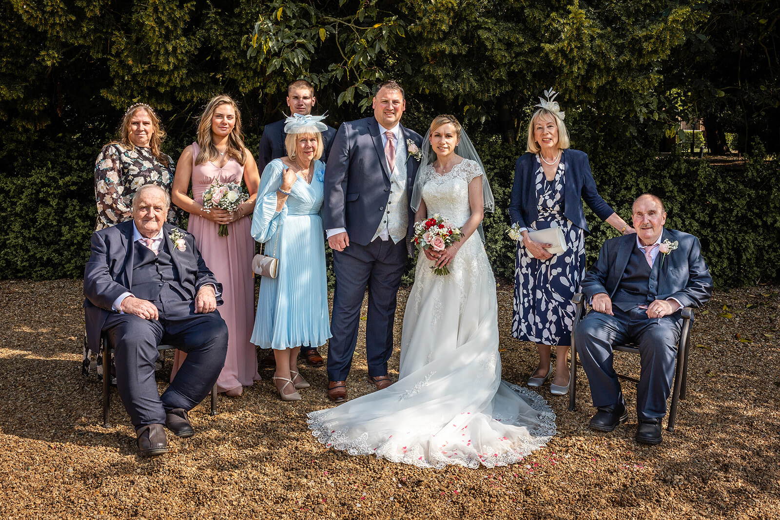 Wedding group photo in garden setting at Holmewood Hall. Wedding photographer Rose Dedman.