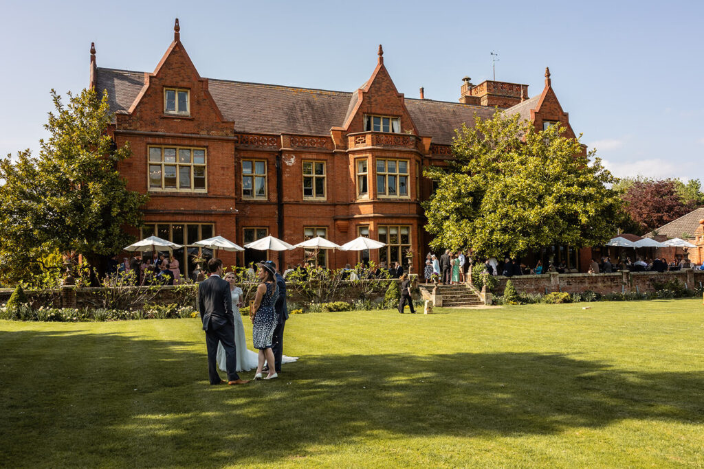 Elegant brick manor house hosting outdoor gathering.