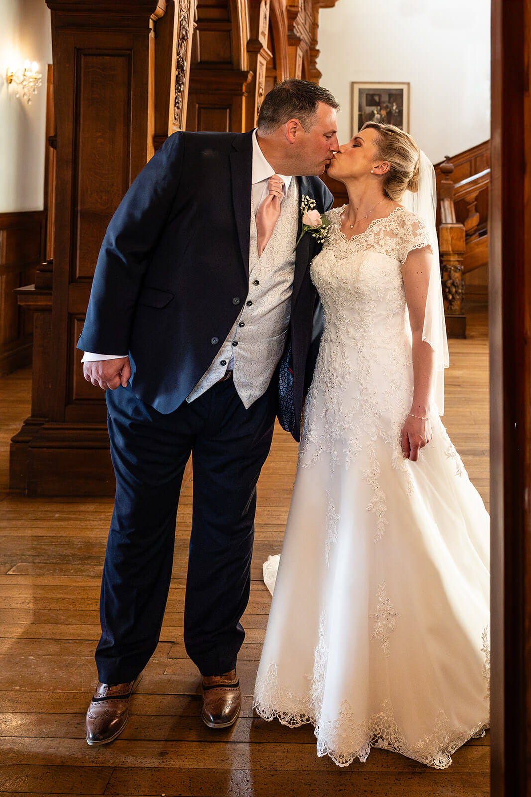 Bride and groom kissing in elegant setting at Holmewood House Cambridgeshire (not Somerset).