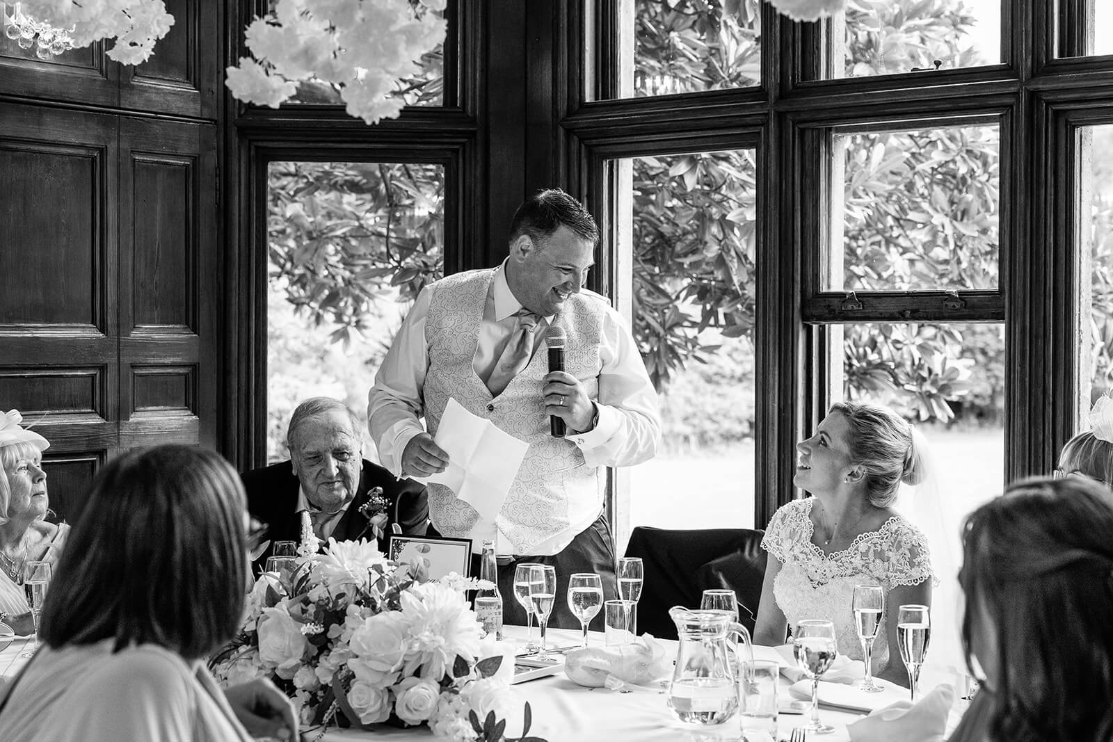 Groom gives wedding speech at banquet table at Holmewood House wedding in Cambridgeshire (not Somerset) wedding. Somerset wedding photographer.