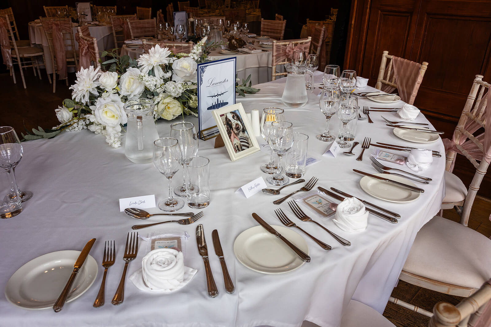 Elegant table setting with flowers and photo frame at Holmewood Hall wedding.