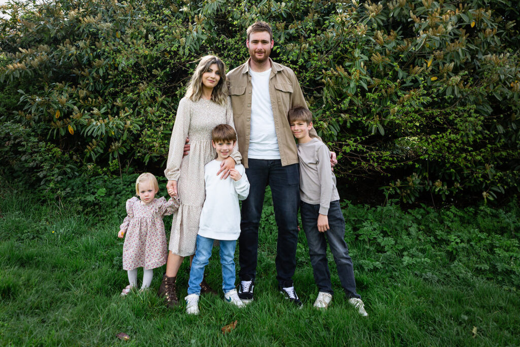 Family posing in garden with trees.