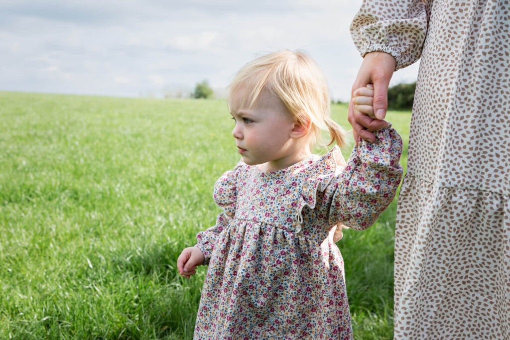 Child holding hand in countryside.