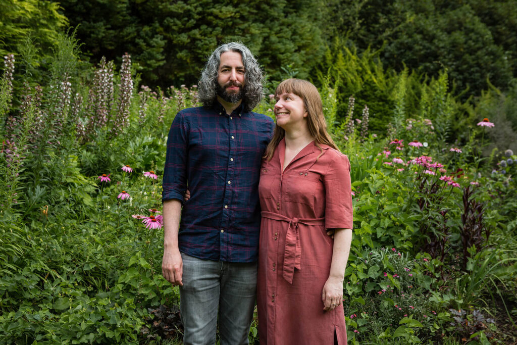 Man and woman standing in lush green garden.