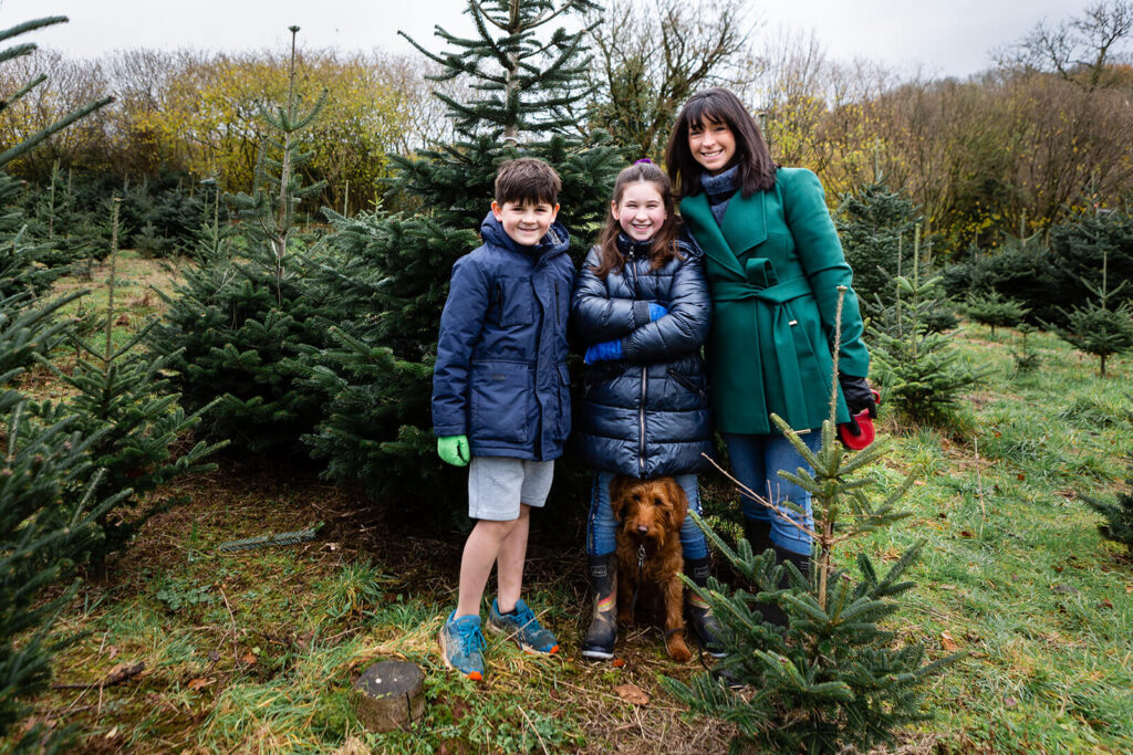 Family and dog in Christmas tree farm.