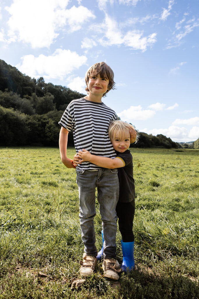 Two children hugging in a grassy field.