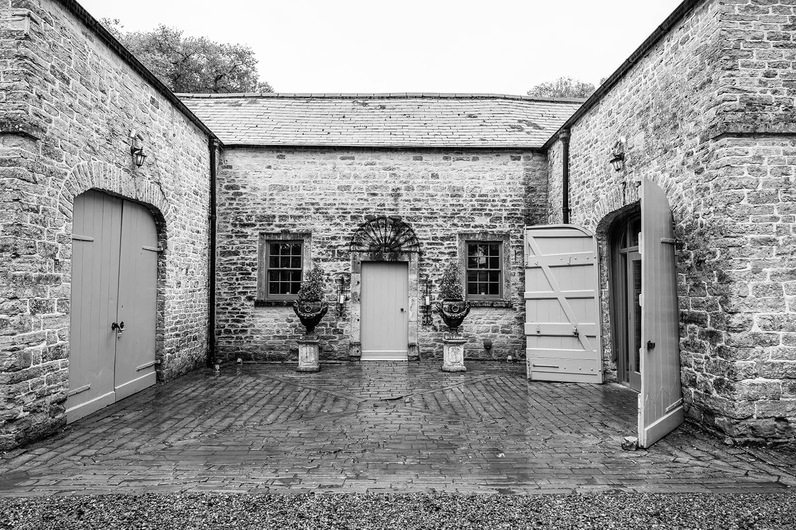 Historic stone courtyard with wooden doors at Pennard House wedding venue, Somerset. By Pennard House wedding photographer Rose Dedman.