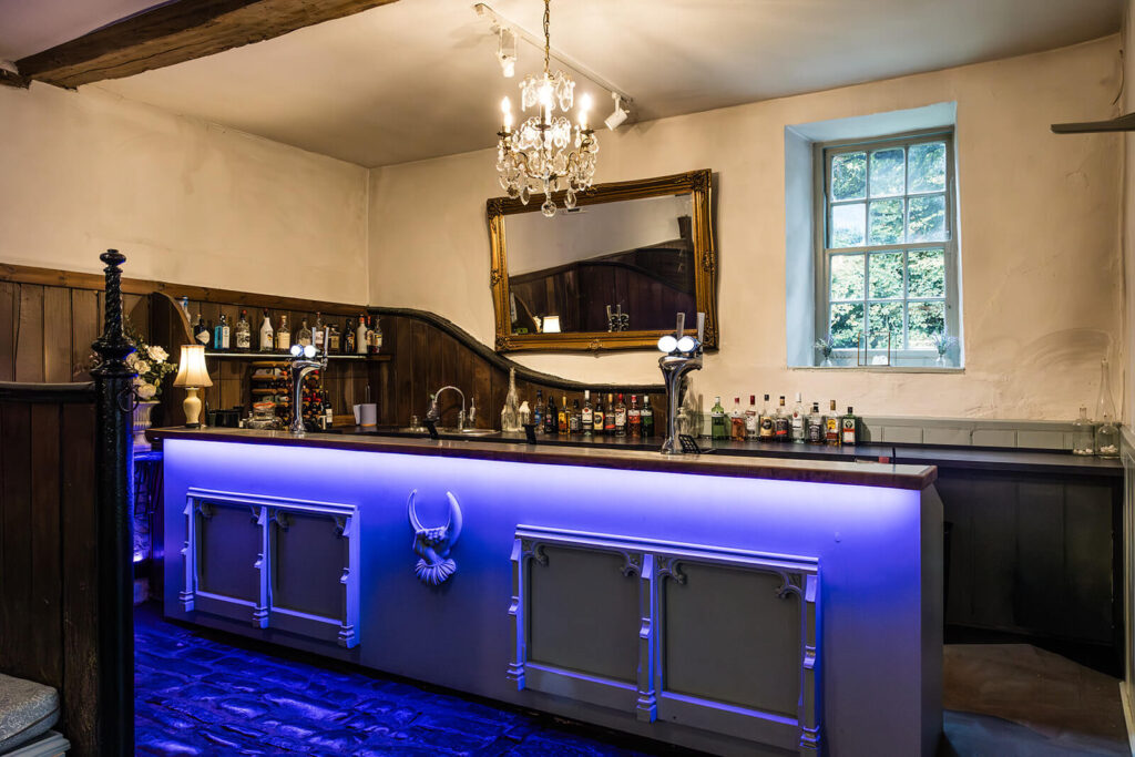 Chic bar at Pennard House wedding venue with chandelier and drinks display. Pennard House Wedding Photographer Rose Dedman.