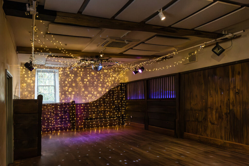 Wood panelled dance floor at Pennard House wedding venue with string fairy lights and disco ball. Pennard House UK Wedding Photographer Rose Dedman.