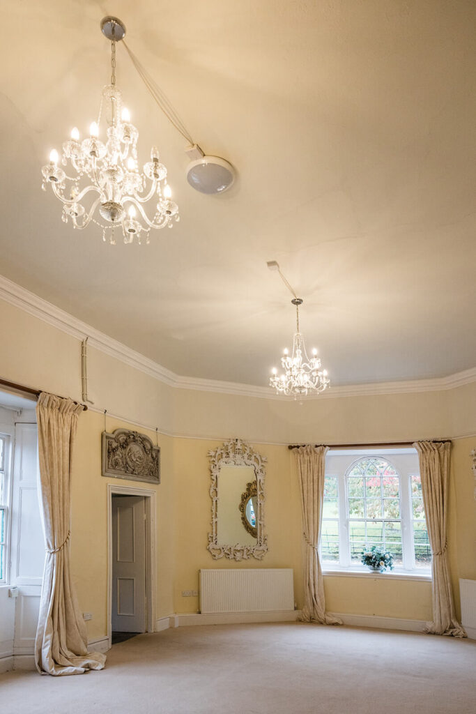 The elegant Napier room at Pennard House wedding venue, with chandeliers and large window. Rose Dedman Photography.