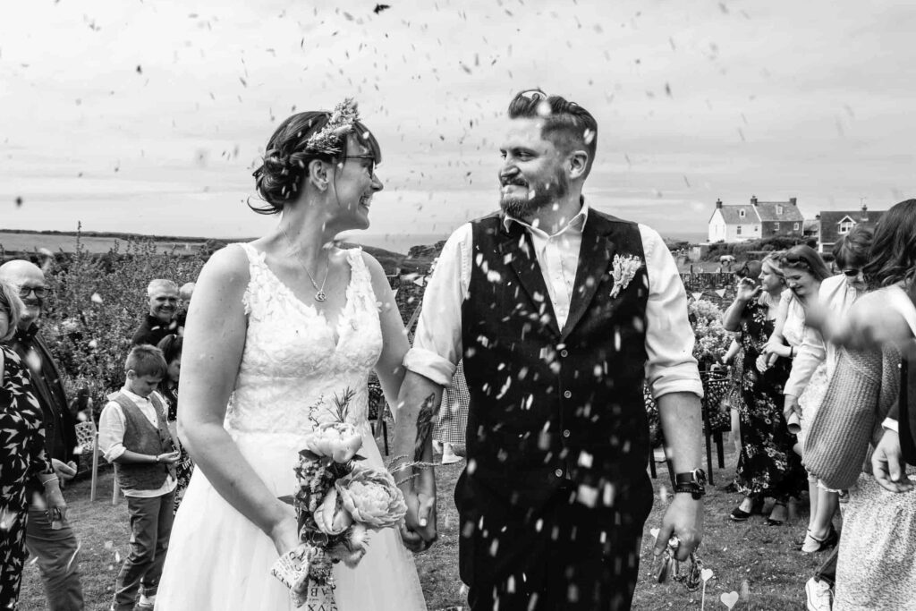 Smiling bride and groom showered with confetti | UK Documentary wedding photographer serving Bath, Bristol, Somerset and beyond