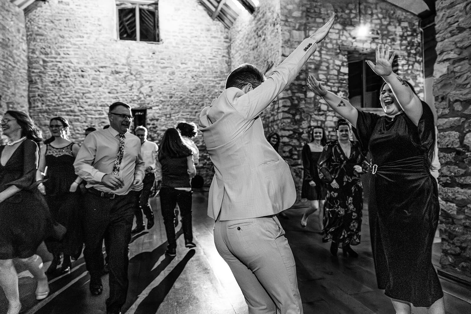 People dancing joyfully at a lively evening wedding party at Priston Mill | Bath wedding photographer