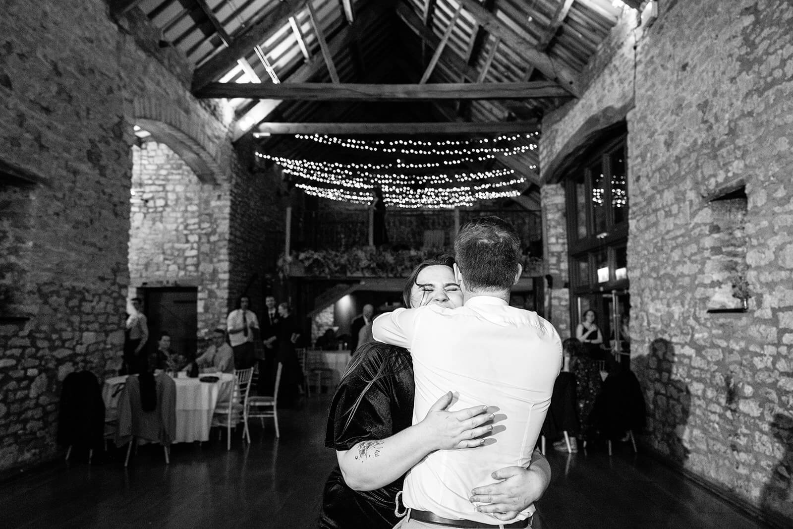 Two people hugging with joy at a Priston Mill wedding evening party | Priston Mill wedding photographer.
