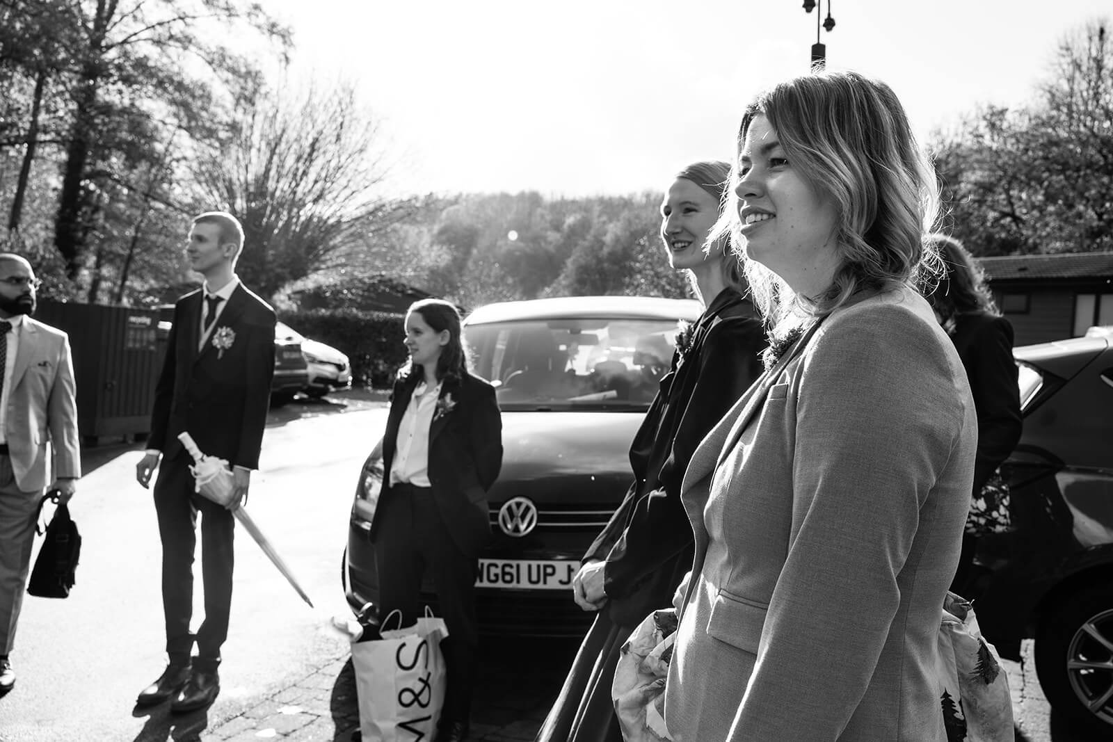 Group of people in formal attire waiting for a view of the bride | Bridal prep at Bath Mill lodges | Bath wedding photographer.