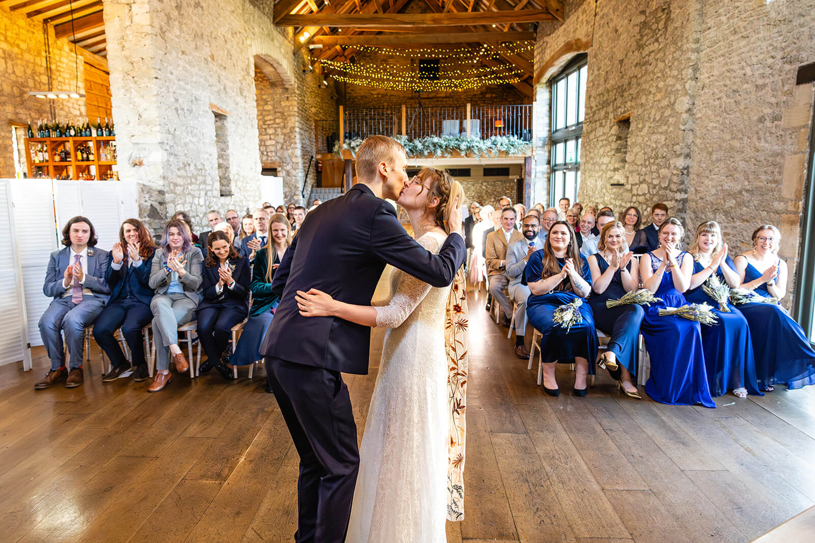 First kiss at Priston Mill Tythe Barn wedding with guests applauding | Priston Mill wedding photographer