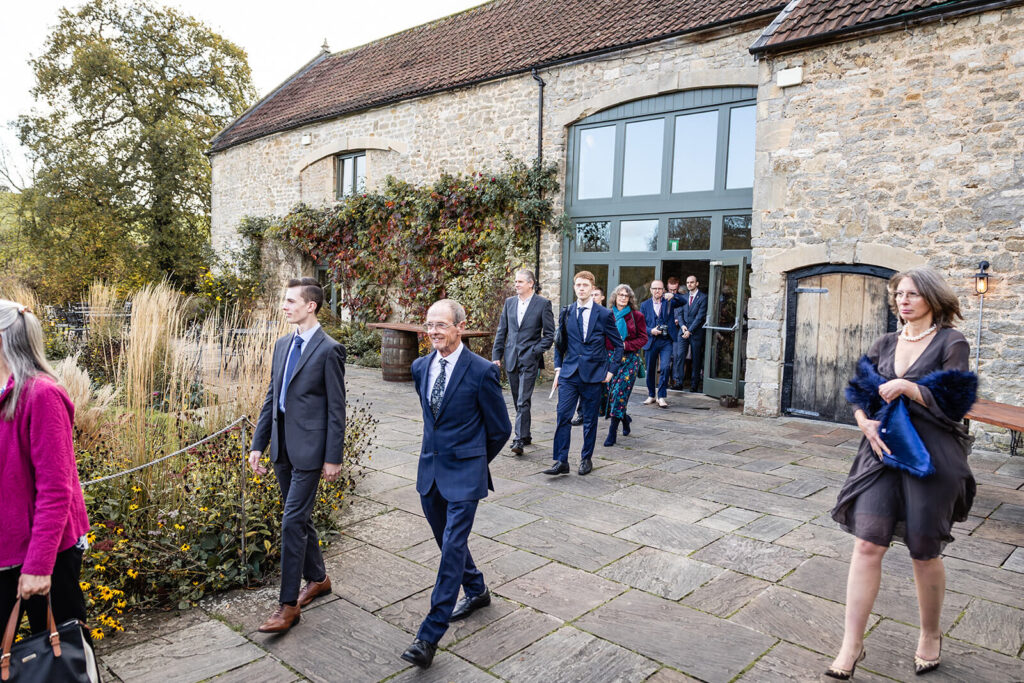 People leaving a stone building in formal attire.