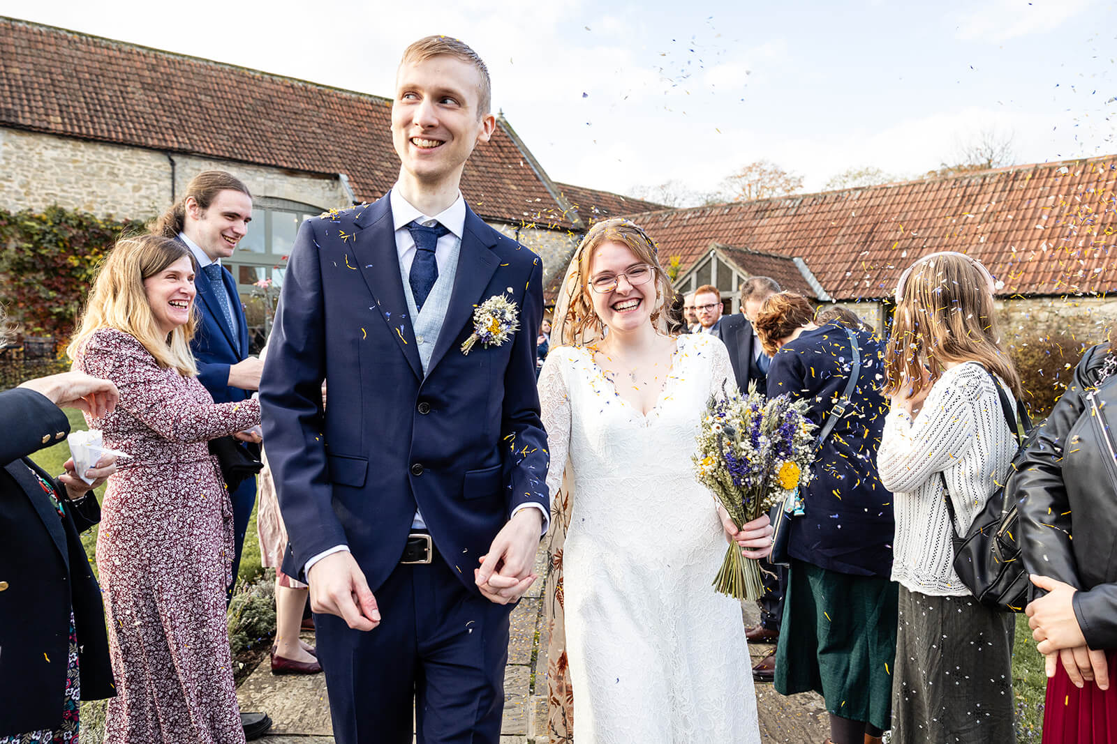 Newlyweds with guests throwing confetti outdoors at Priston Mill | Bath wedding photographer