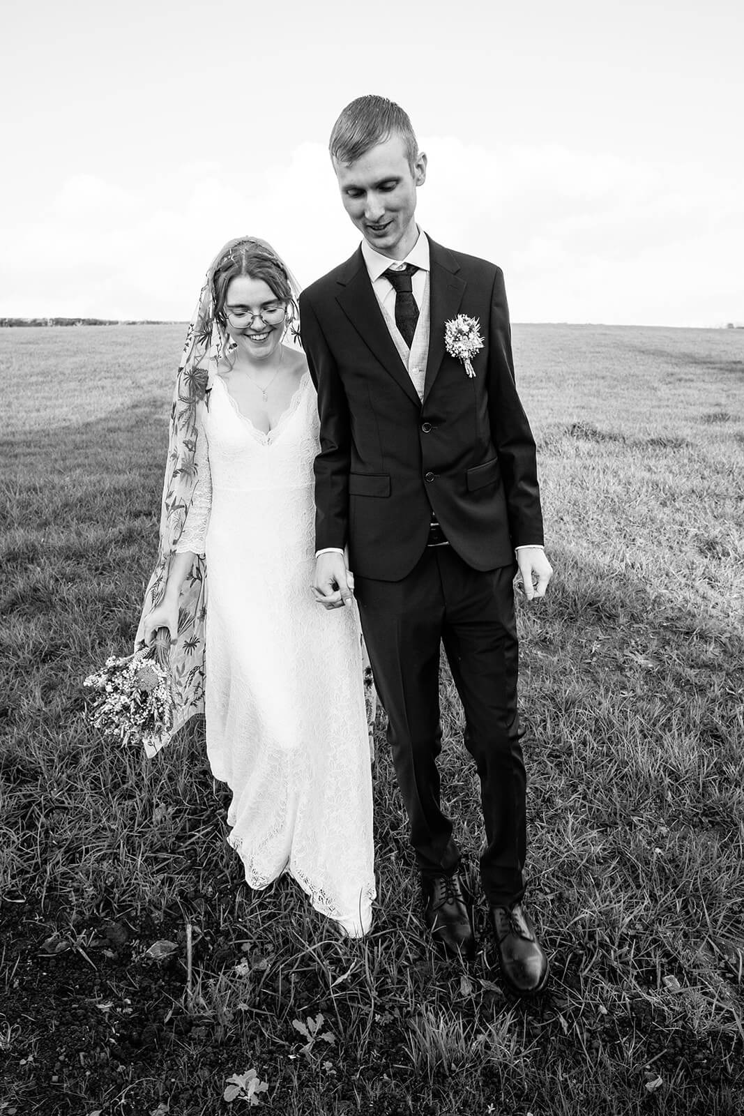 Wedding couple walking in countryside field at Priston Mill | Couple portraits by Priston Mill wedding photographer Rose Dedman