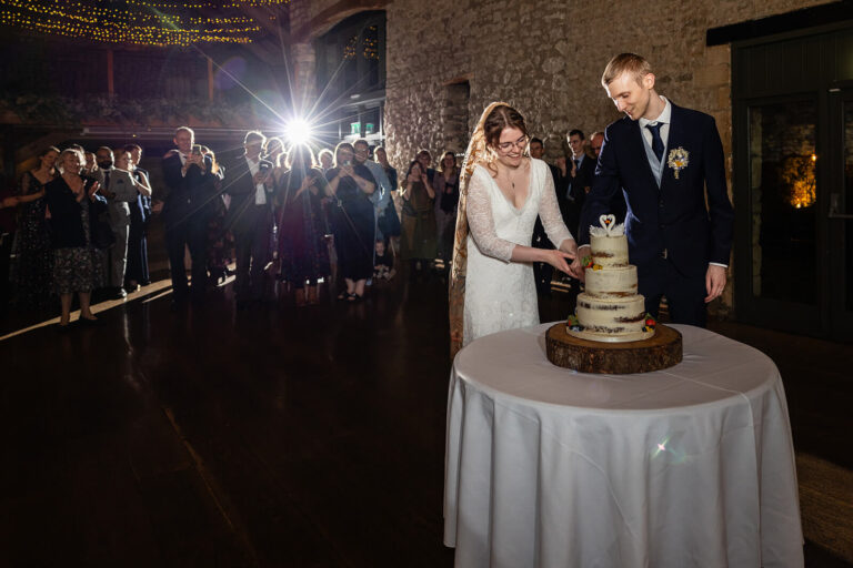 Bride and groom cutting wedding cake in restaurant.