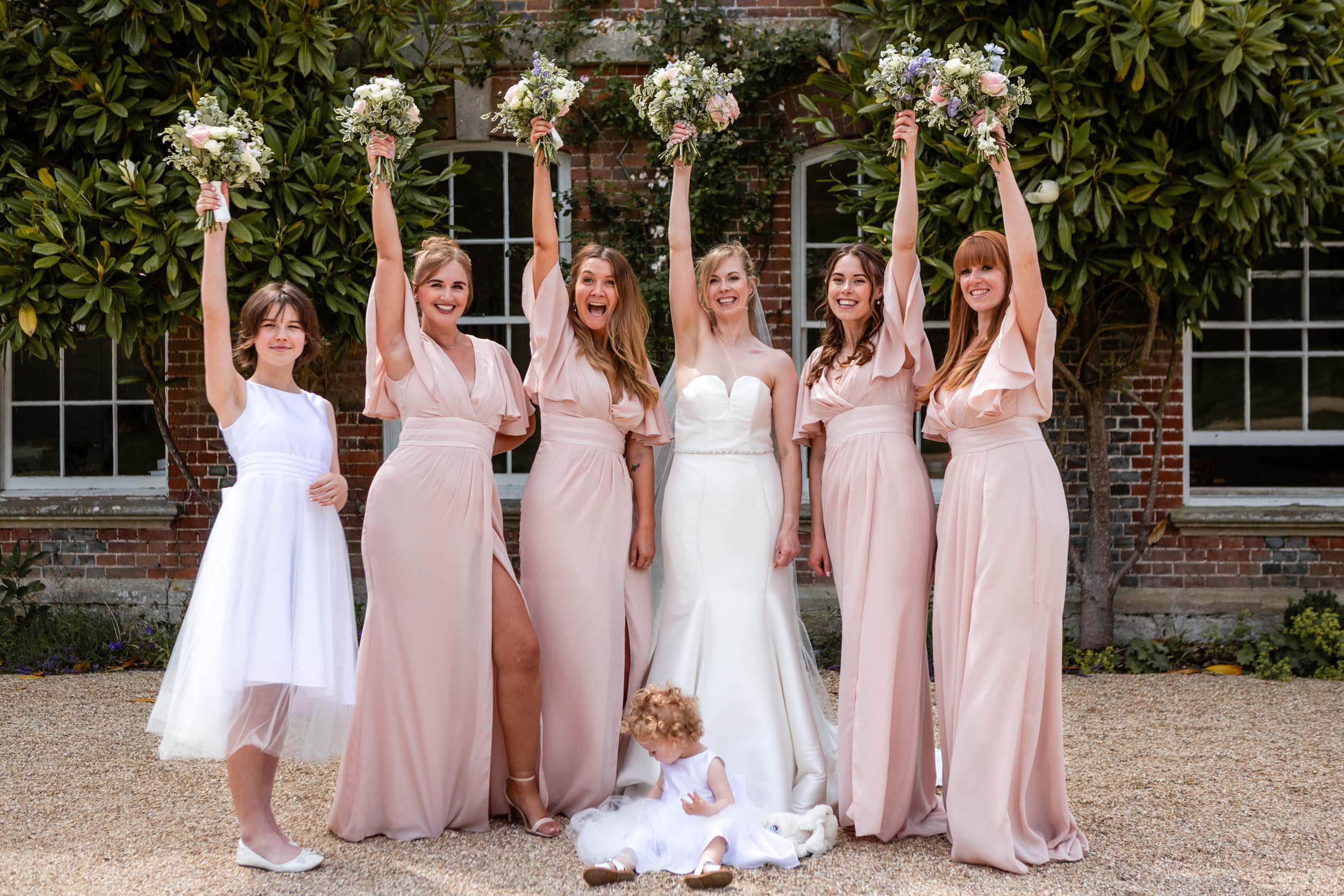 Bridal party celebrating with bouquets outside Syrencot House.