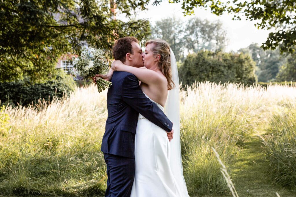 Bride and groom kissing in a grassy field at Syrencot House