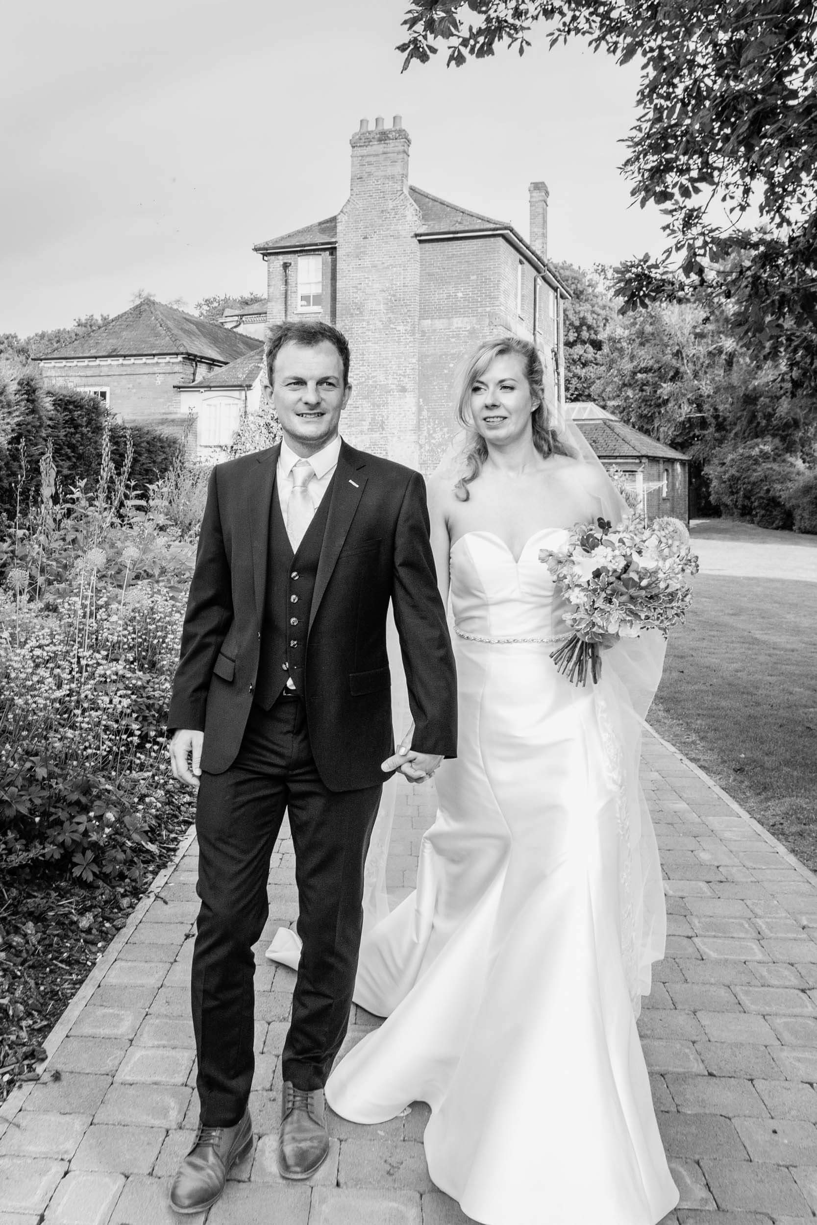Bride and groom walking outdoors in black and white at Syrencot House wedding.