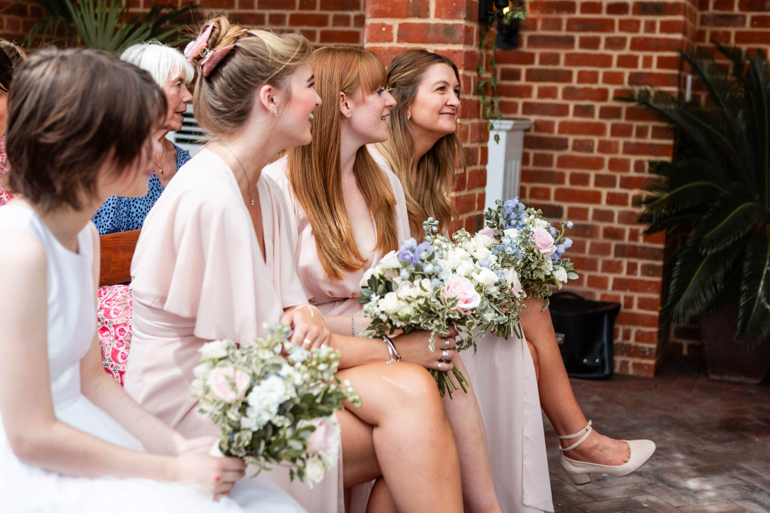 Bridesmaids smiling with bouquets at a wedding ceremony at Syrencot House, Wiltshire.