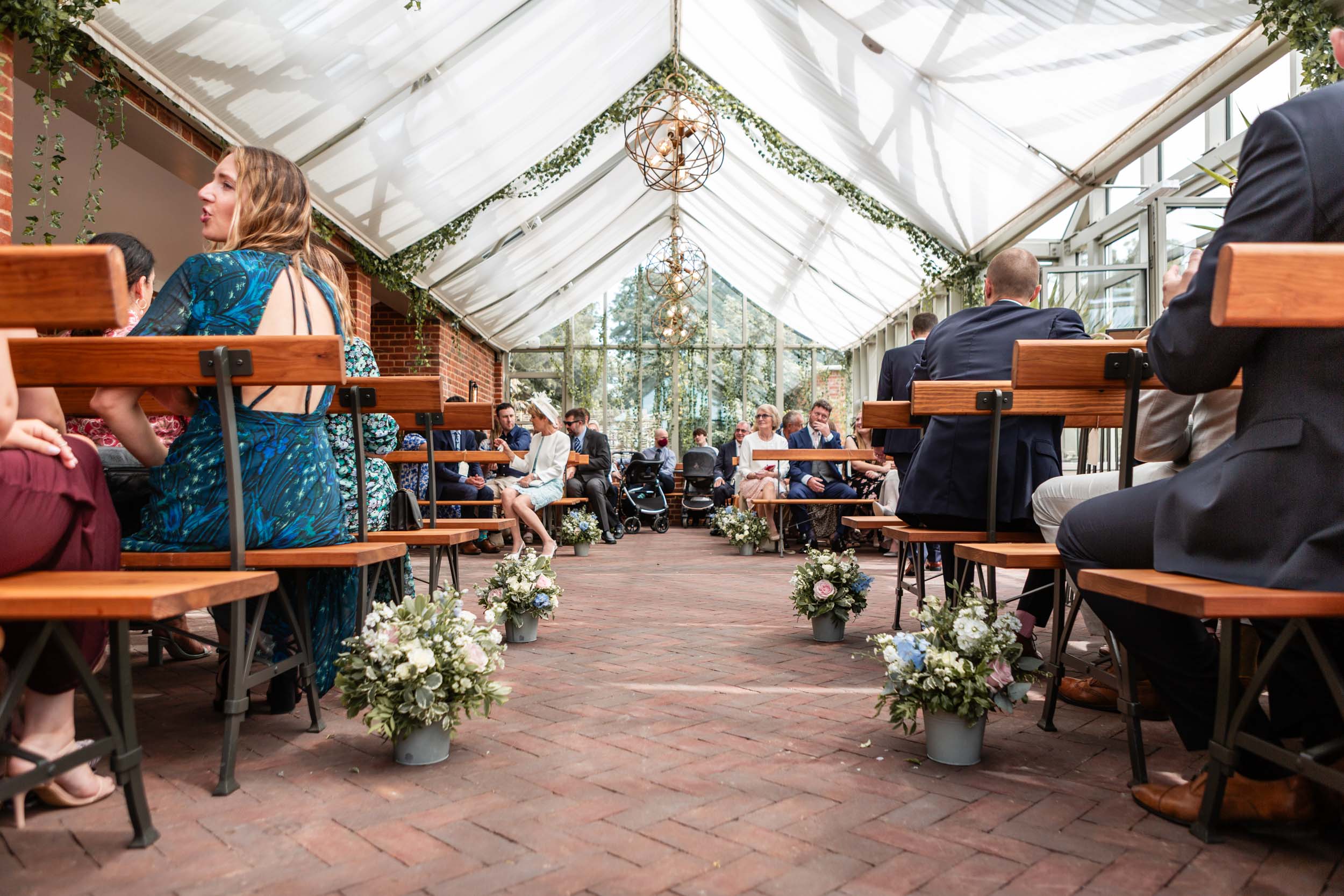 Guests seated in greenhouse-style wedding venue | Summer Wedding Photography at Syrencot House