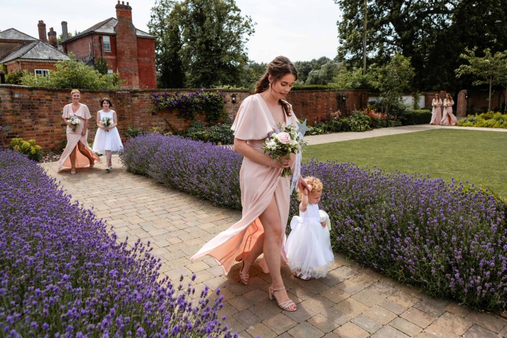 Bridesmaids and child walking through lavender garden.