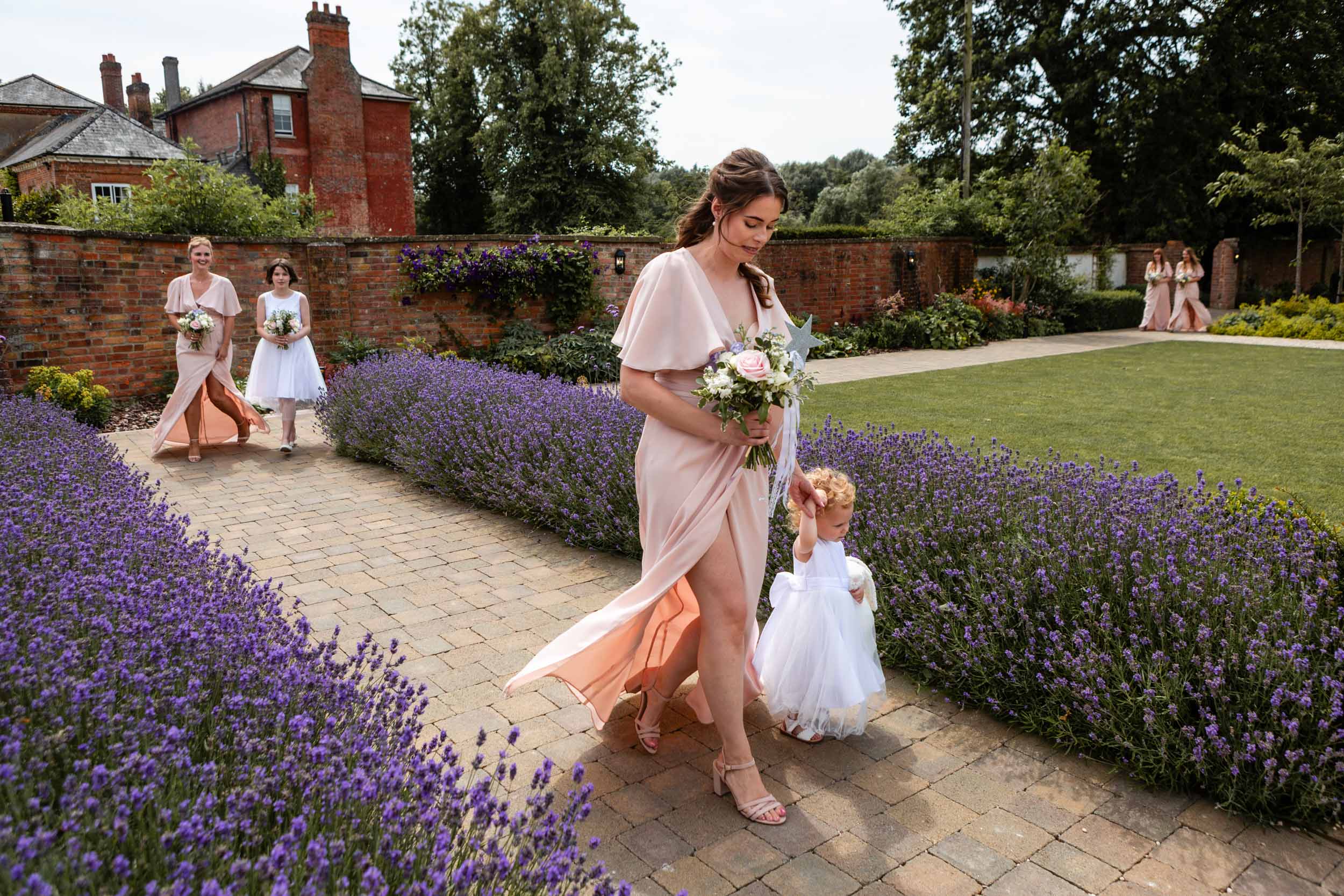Bridesmaids and child walking through lavender garden.
