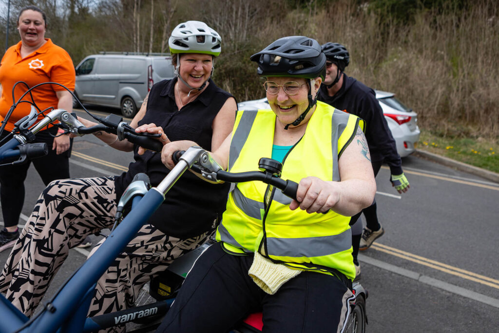 Two women cycling, smiling together.