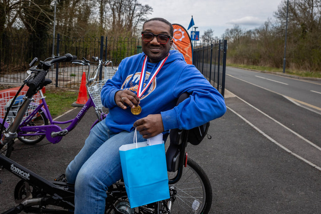 Man with medals on tricycle smiling.