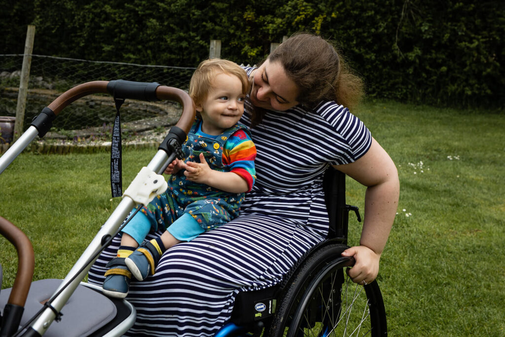 Child sitting with woman in wheelchair outdoors