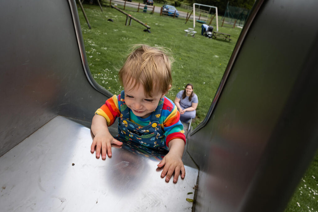 Child climbing up slide, smiling