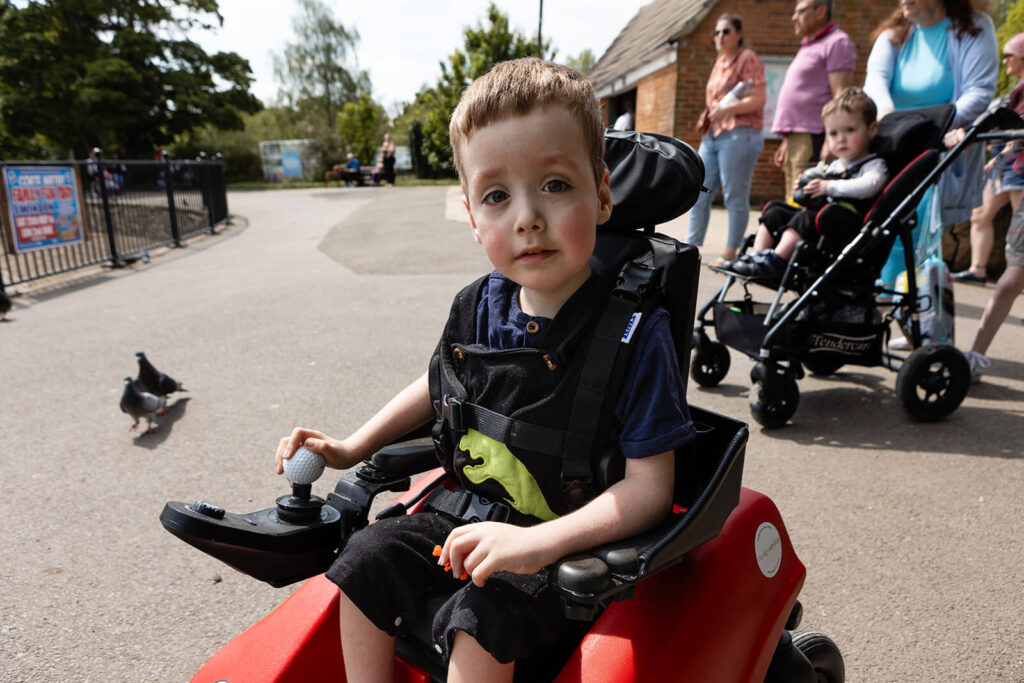 Child using wheelchair outdoors at park.