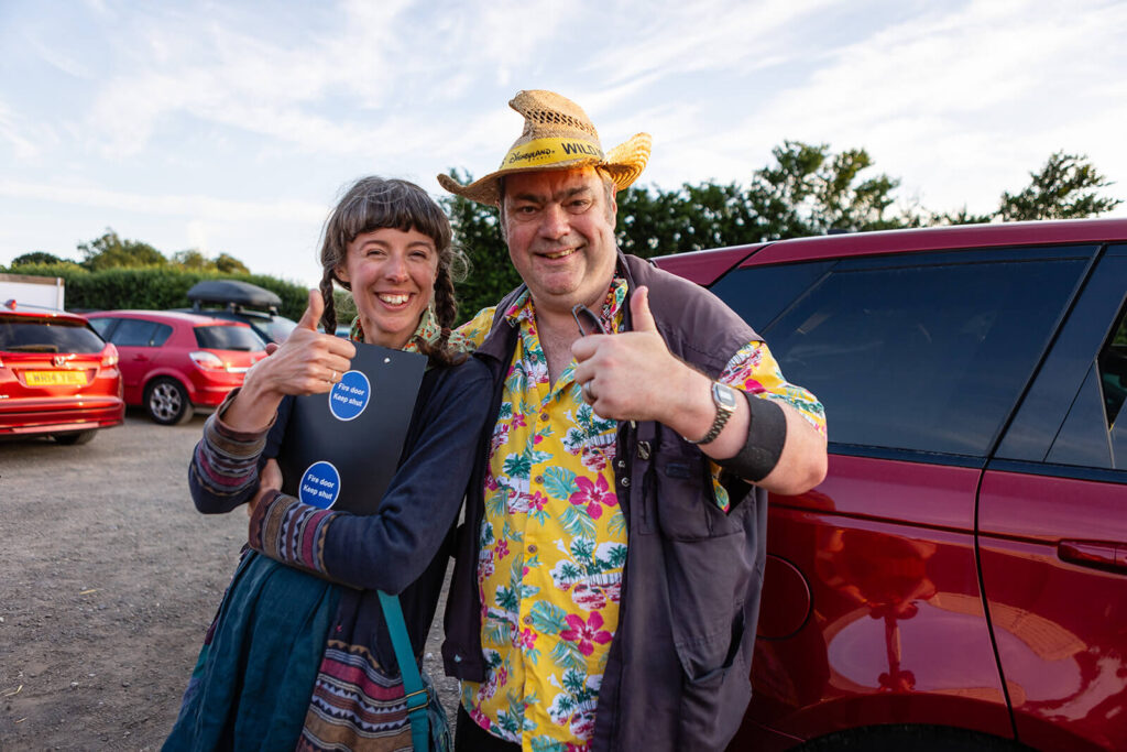 Smiling duo with thumbs up in car park