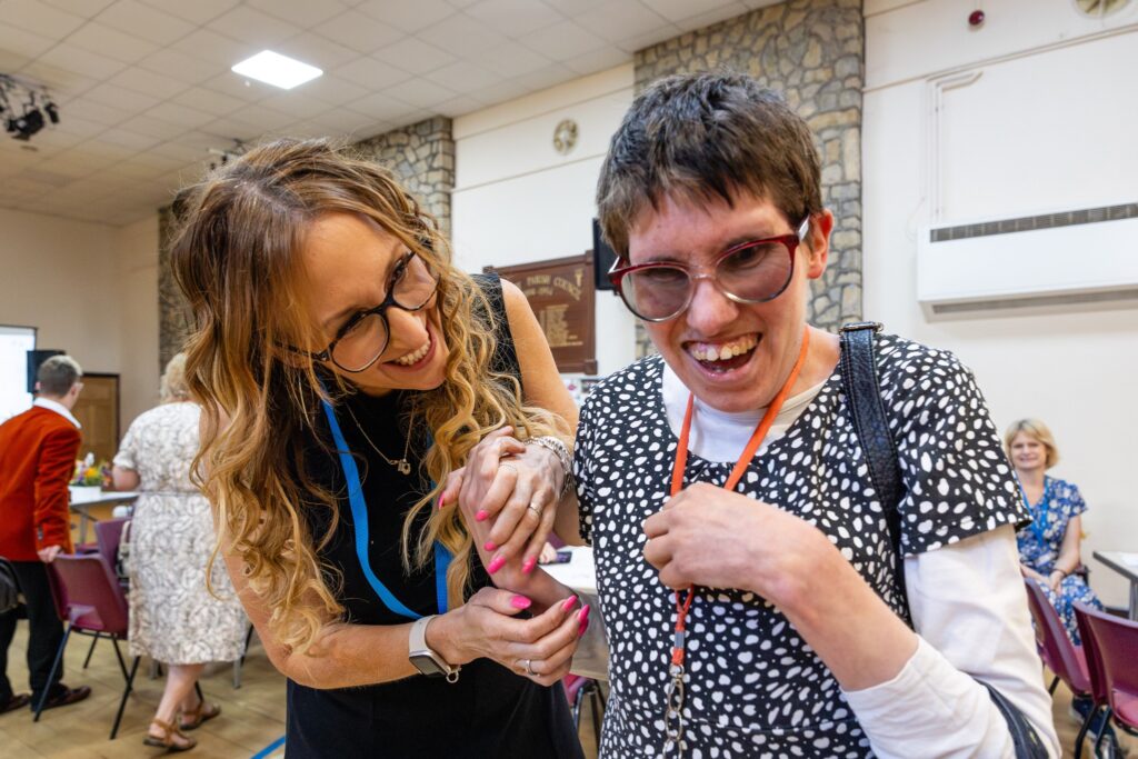 Two women laughing and embracing joyfully | One is a support worker and one woman has learning disabilities | Charity photography