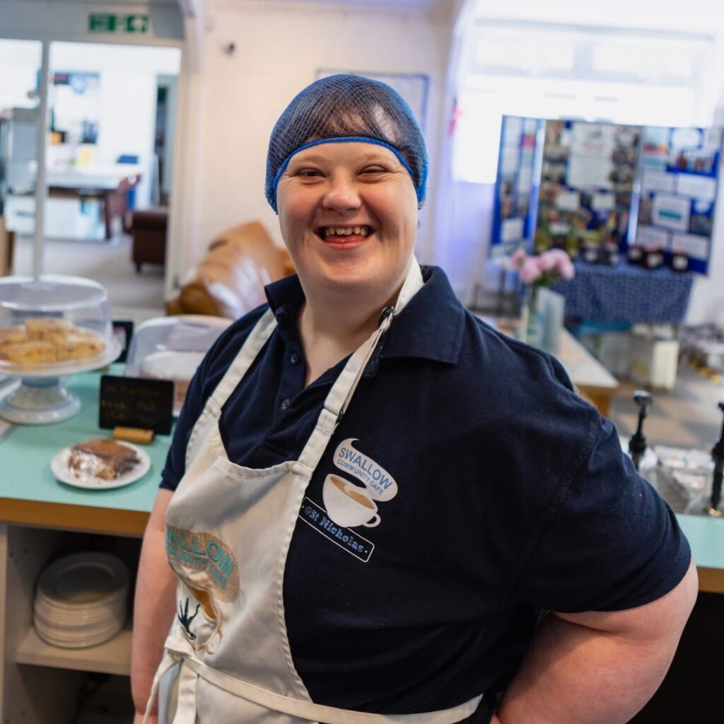 Smiling cafe worker with Down syndrome wearing an apron | Charity photoshoot