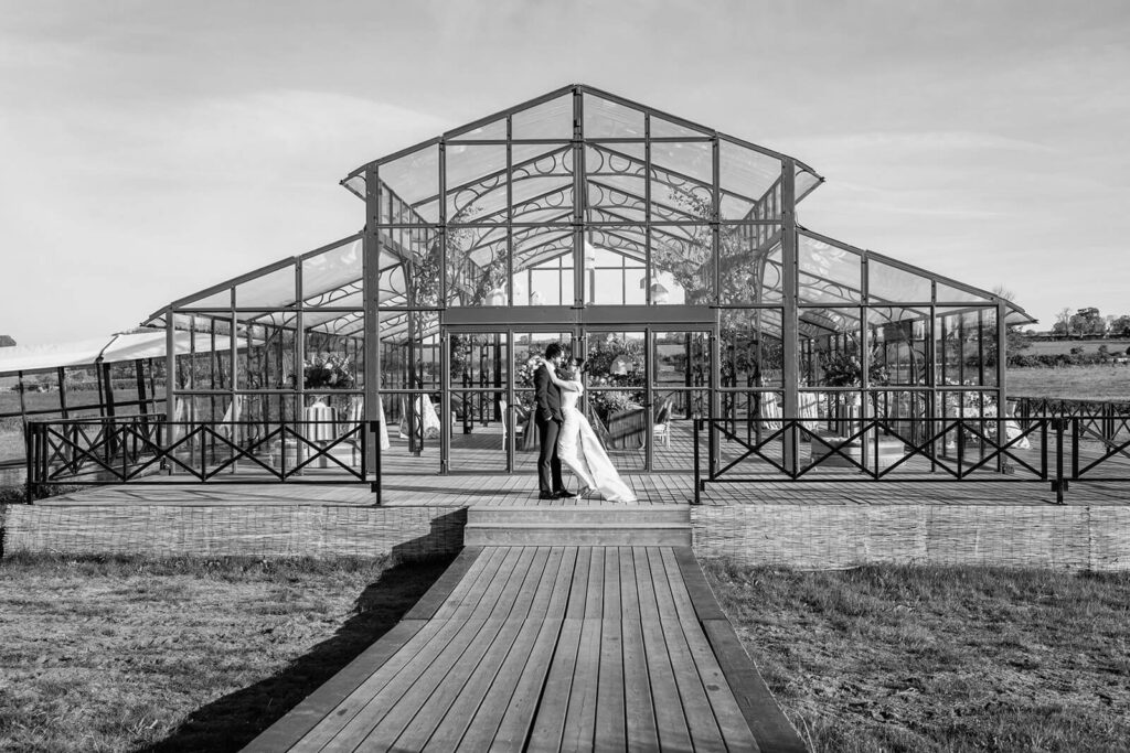 Couple embracing outside glasshouse venue.